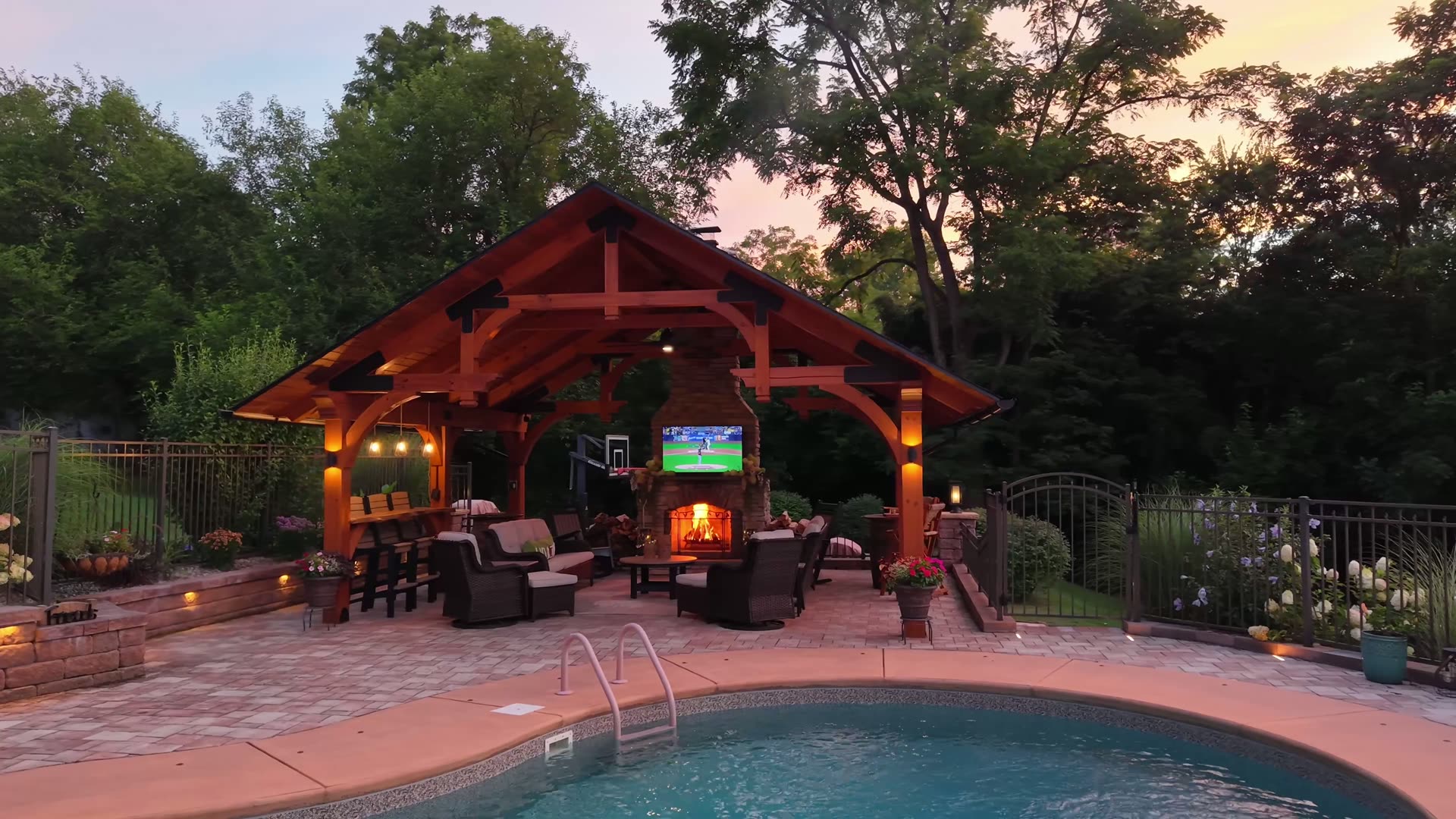 Timber-frame pavilion with stone fireplace and outdoor lounge at night