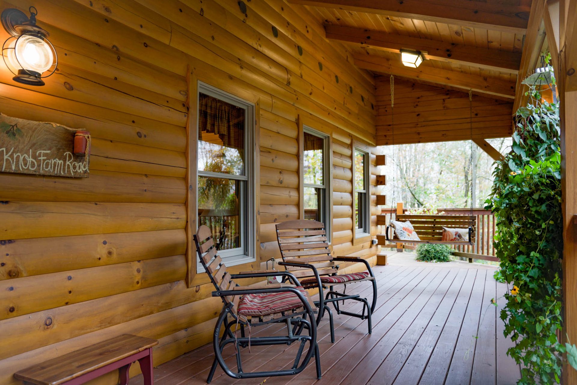 Rancik log home covered porch with rocking chairs and porch swing
