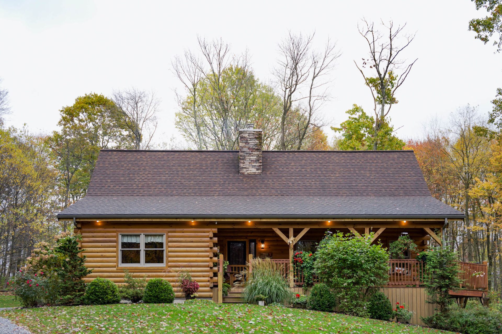 Front elevation of the Rancik log home with stone chimney and covered porch