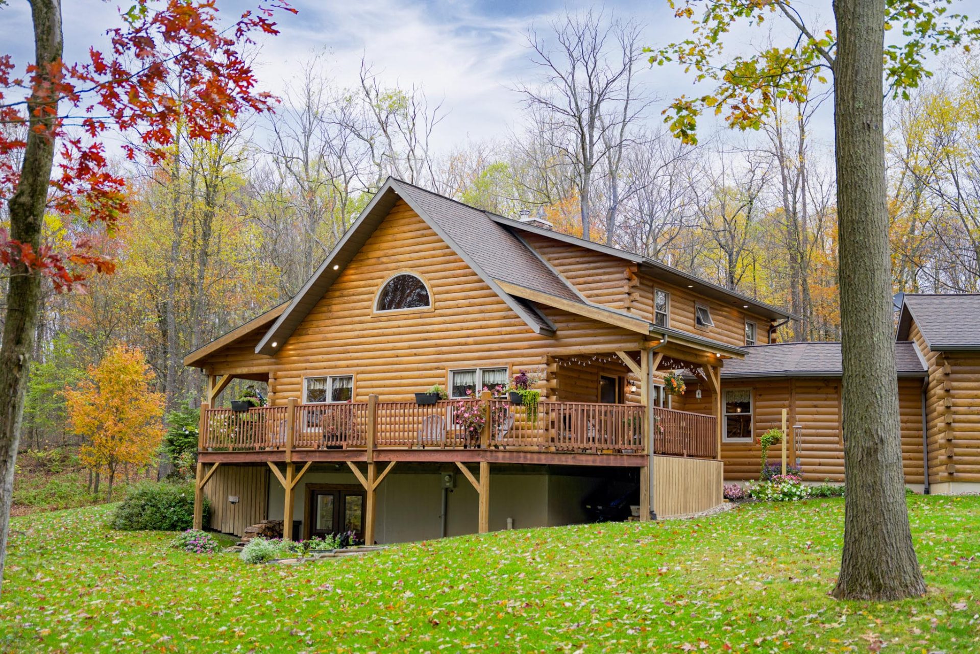 Rancik log home exterior with covered deck and autumn foliage