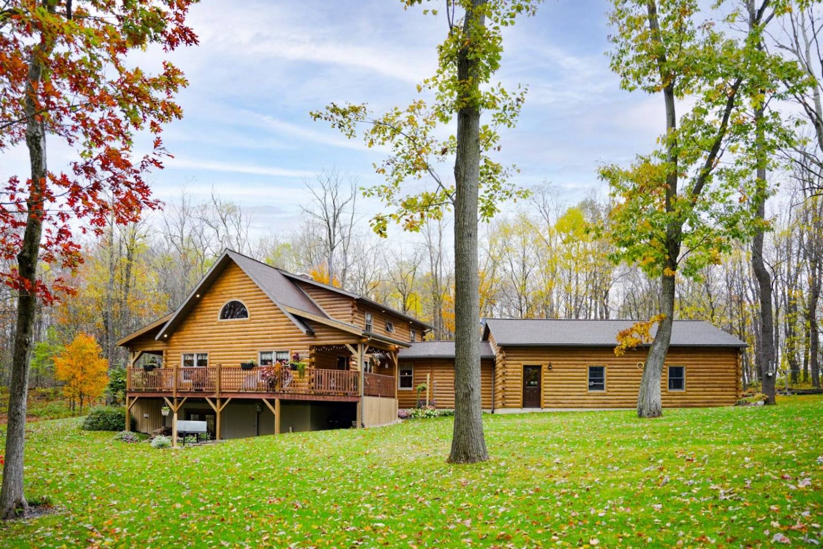 Custom log home with attached garage surrounded by autumn trees